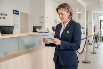 Employée La Poste en uniforme consultant une brochure de points fidélité au comptoir d'un bureau de poste moderne